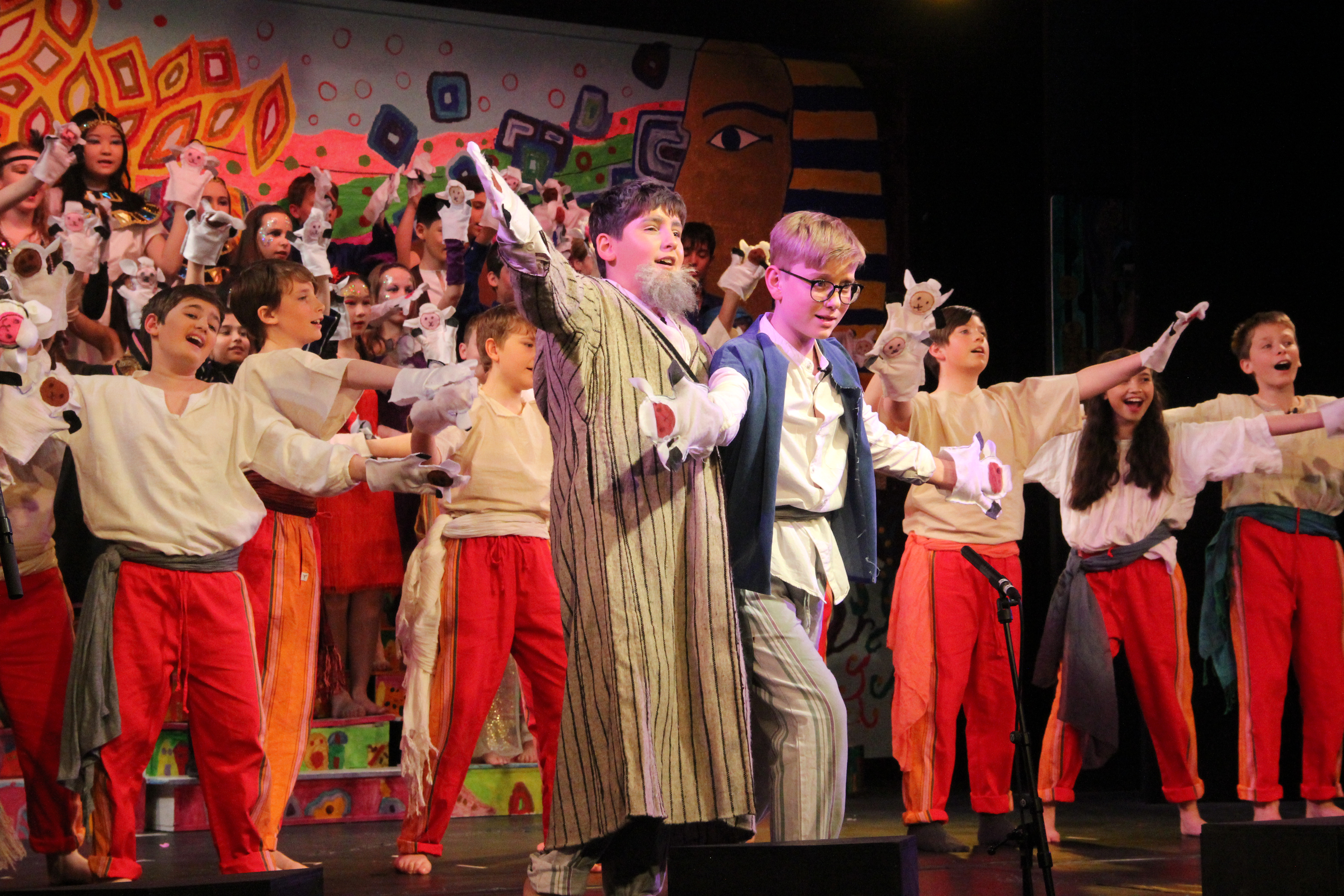 children dressed up and acting on stage in joseph and the amazing technicolor dreamcoat