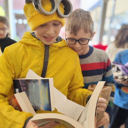 children in costume looking at a book