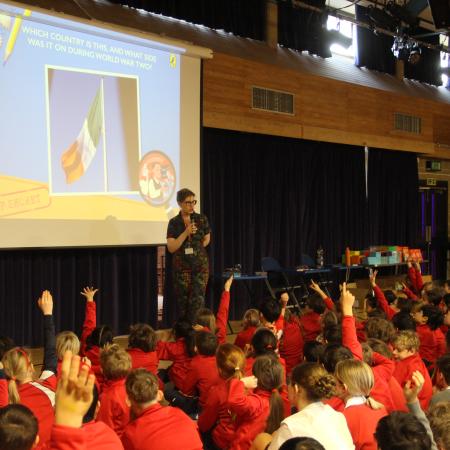 children with hands up listening to an author