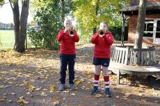 two children playing the trumpet in the school playground