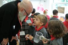 an author bending down to talk with young children in a classroom