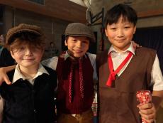 three children hugging in Victorian costumes in a hall