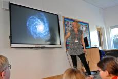 speaker looking at a slide of the Milky Way and talking to children