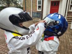 children wearing racing suits and helmets looking at each other