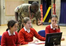 RAF soldier teaches pupils how to code with python in a hall