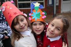 three children hugging in the playground with christmas jumpers on