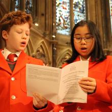 two school children singing in a chapel