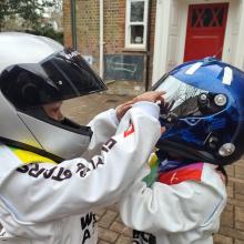 children wearing racing suits and helmets looking at each other