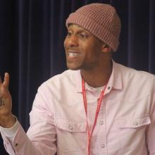 performance poet Kimba speaking with his right arm raised