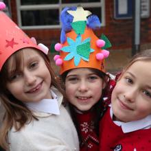 three children hugging in the playground with christmas jumpers on